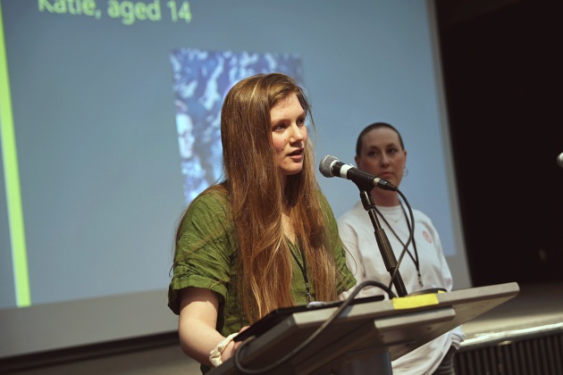 Two women standing at a podium speaking into a microphone and presenting a speech.
